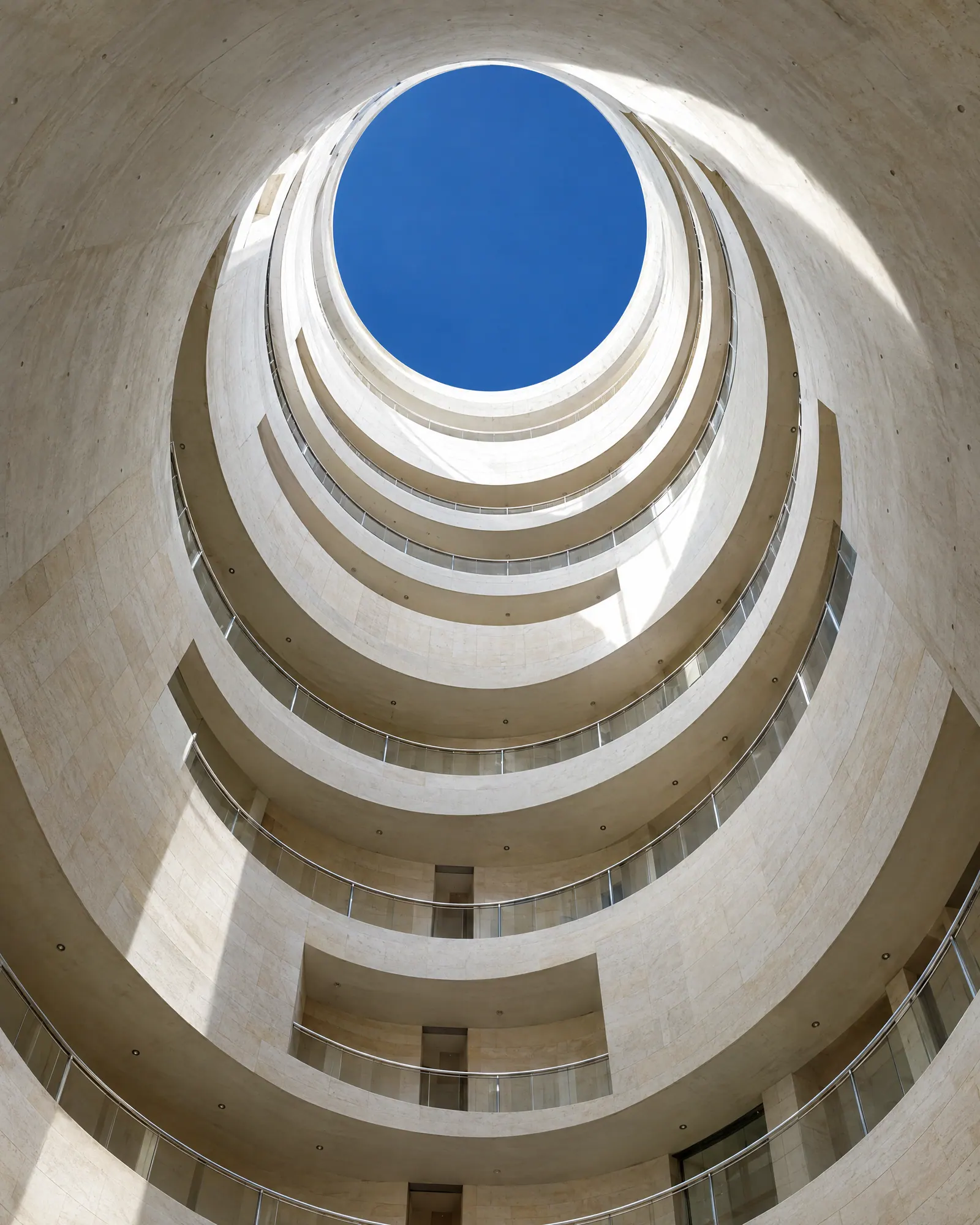 Looking up through a cylindrical light well toward a circle of blue sky